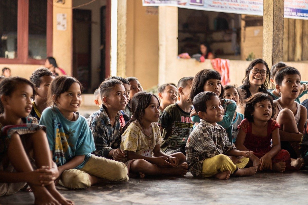 A large group of children sitting together outdoors