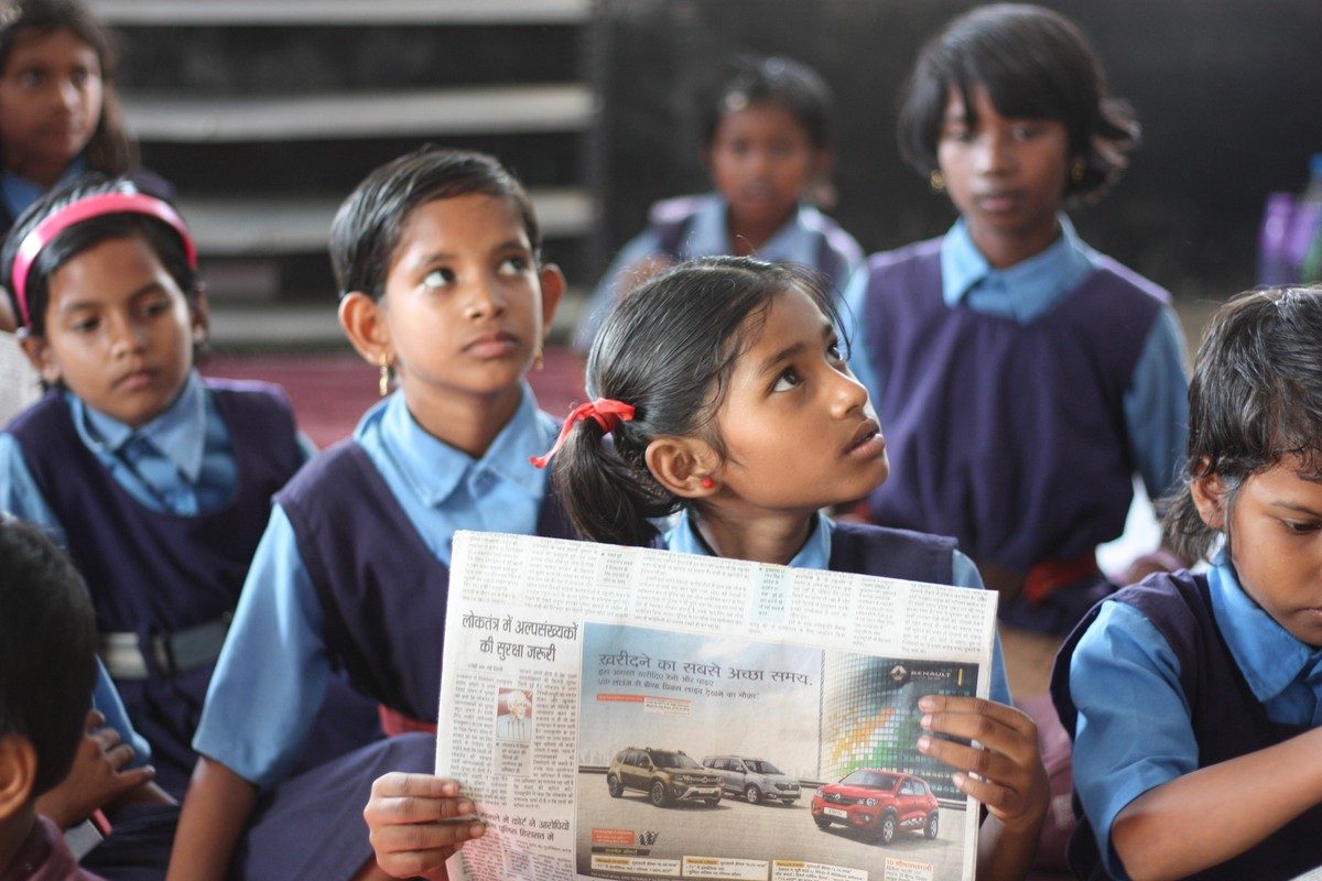 Students in uniform reading a newspaper together